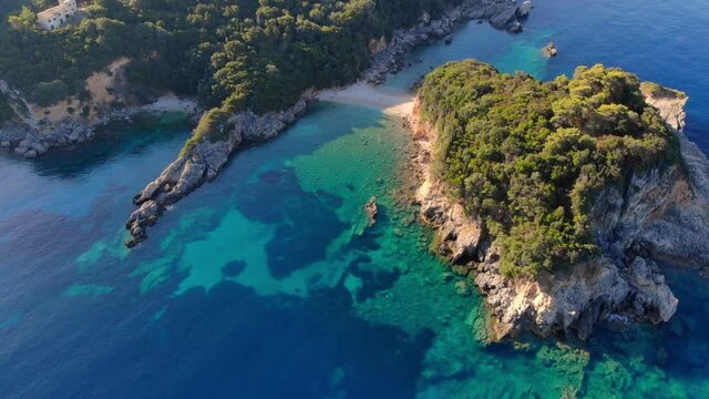 Panorama of beautiful coast of Corfu island at sunrise. Aerial view. Small beach surrounded by rocks covered with trees.