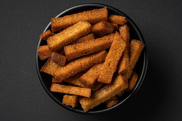 Bowl of rye croutons on black background
