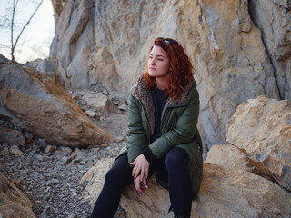 a redheaded woman walking along a mountain road in early spring