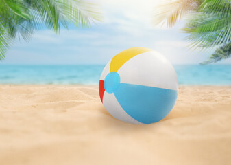Obraz premium Colorful beach ball on sandy coast near sea