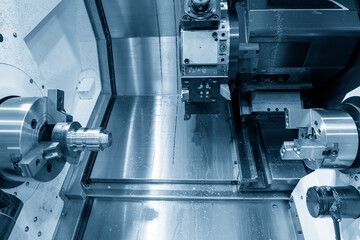 The  double-turret CNC lathe machine  cutting the metal shaft parts.