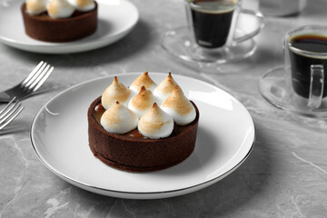Delicious salted caramel chocolate tart with meringue served on light grey marble table, closeup