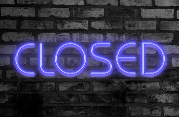 Glowing purple neon closed sign on grungy black brick wall