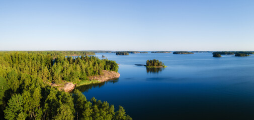 Fototapeta na wymiar Aerial Panorama of Scandinavian green pine tree forest, dark blue sea with few small islands, Baltic Sea on horizon. Sunny day, Northern Scandinavia. Drone photo.
