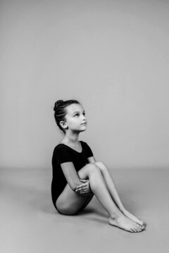 a beautiful little gymnast is sitting on an isolated background. Black-and-white photograph