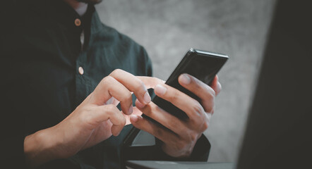 Businessman using a smartphone to view the stock market.Close-up image of male hands using smartphone at home.social networks concept.Concept of young people working mobile devices.
