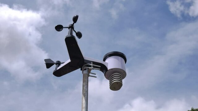 time lapse solar weather station for meteorological research with indicator and wind speed, rain gauge, temperature control, bottom view with passing clouds in the background