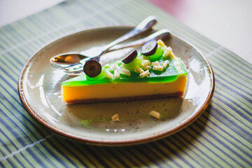 Slice of green lime cheesecake decorated with white chocolate and blueberries. Summer dessert pie on a green striped placemat.