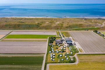 Luftaufnahme vom einem Campingplatz im Vordergrund, dahinter der Deich und die Nordsee bei...