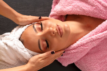 Woman hands provides professional beauty face treatment on clean young woman face in lying position in beauty studio