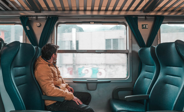 Young boy alone in the wagon, looking out the window of an old train. Explorer trip around the world.