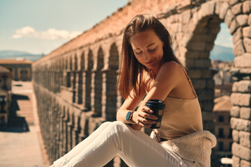 Woman sit outdoor, Roman Aqueduct on background. Segovia, Spain
