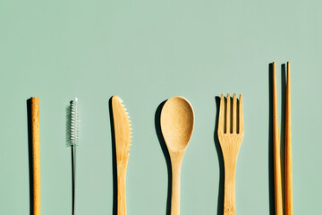 Eco friendly bamboo cutlery set on light green pastel background with geometric shadows. Zero waste, plastic-free  lifestyle concept.