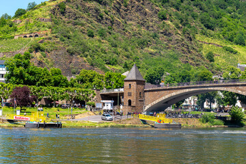 Obraz premium Cochem, Germany, June 13, 2021. People walking on the bridge and the sidewalk along the river in the tourist town of Cochem on the Moselle in Rhineland-Palatinate, Germany.