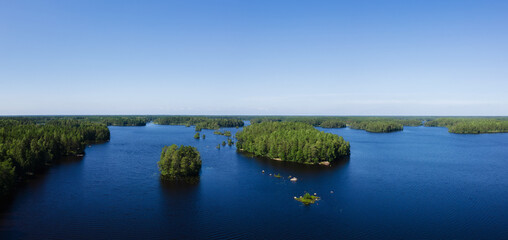 Aerial view of blue lake and green forest on a sunny summer day in Finland.  Sunny day, blue sky. Drone 
photo.