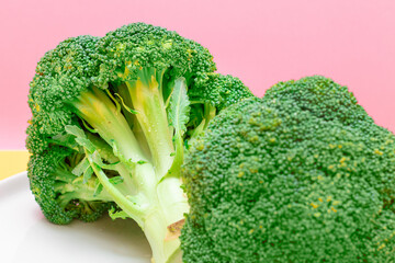 Two Fresh and Raw Pieces of Broccoli on White Plate. Uncooked Green Cabbage. Vegan and Vegetarian Culture. Raw Food. Healthy Eating and Vegetable Diet