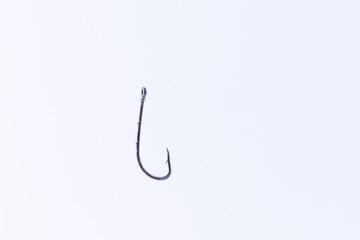 Black Fishing Hook Hanging on a Fishing Line Against a White Background