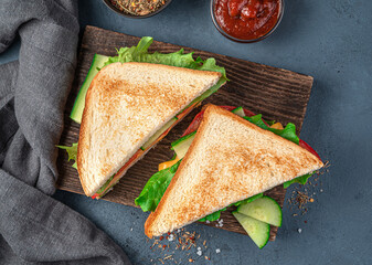 Sandwiches with cheese, vegetables and ham on a wooden board on a dark blue background. Top view, close-up.