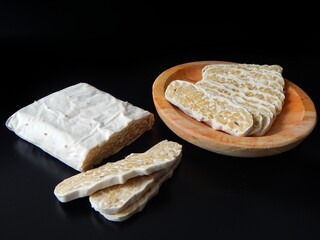 Raw tempeh or tempe. tempe slice on wooden cutting board. tempe is a traditional Indonesian food made from fermented soybeans. Fermented food. vegan food. macro photography.	