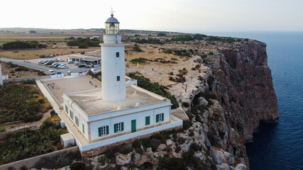 Aerial view of the Far de la Mola, a lighthouse at the southeastern tip of Formentera island in the Balearic, Islands, Spain - White lighthouse at the top of a cliff in the Mediterranean Sea