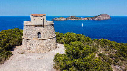 Fototapeta na wymiar Torre den Valls, aka Torre de Campanitx, a defensive round tower at the easternmost point of Ibiza in the Balearic Islands, Spain - Stone fortress with a view on the island of Tagomago