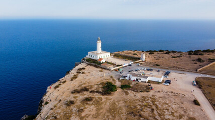 Fototapeta na wymiar Aerial view of the Far de la Mola, a lighthouse at the southeastern tip of Formentera island in the Balearic, Islands, Spain - White lighthouse at the top of a cliff in the Mediterranean Sea