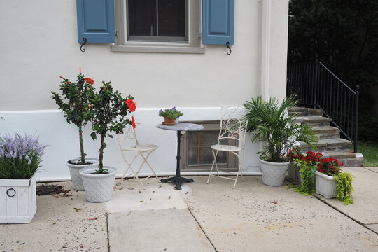 The flowers and the table and chairs have been arranged in front of the house with blue shutters in Doylestown, PA.