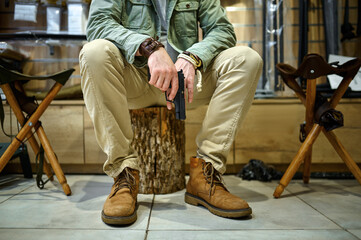 Man with pistol sitting on stump in gun store