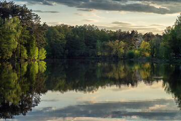 Beautiful sunset on the lake with a reflection on the water surface. Lake in the forest.