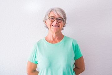 portrait of one pretty old and mature woman looking at the camera smiling and laughing - happy senior lady with a white background