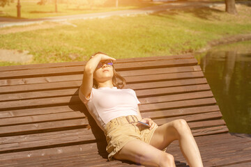 summer heat, teen girl roasts in the sun on a bench in the park