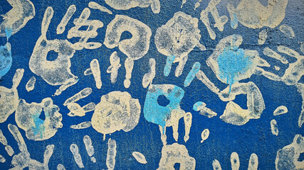 Handprints and dripping paint on the textured background of an old painted wall.