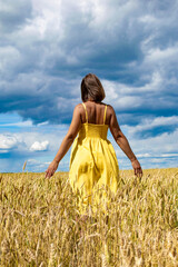Naklejka premium A young girl dances and enjoys life in the wheat field. Lifestyle concept.
