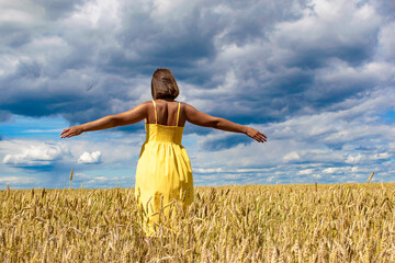 A young girl dances and enjoys life in the wheat field. Lifestyle concept.