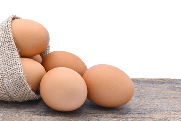 chicken eggs in burlap sack on old wood and white background close up