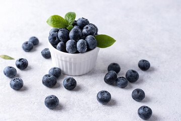 Ripe blueberries in a bowl on a white background, summer berries.