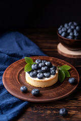 Berry dessert, blueberry tart on dark wooden background.