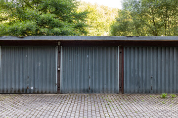 Fototapeta premium a three car garage standing alone on a roadside. a rustic old garage with steel doors. Symmetry in the architecture. 