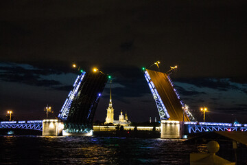 Fototapeta na wymiar St. PETERSBURG, RUSSIA-July, 2021: an open palace bridge with neon illumination on the Neva River and reflections against the black night sky