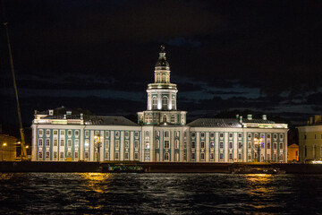 Fototapeta na wymiar Saint Petersburg, Russia, July, 20, 2021: frontal view of the historical palace-museum of the Kunstkamera with evening illumination and the Neva River against the black night sky