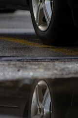 crisp Reflection of a back wheel of a car in a puddle of water in a parking lot after a rainy day