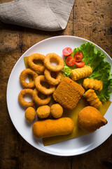 dish with mixed fried food, potato croquettes, stuffed olives, breaded mozzarella, onion rings, arancini. typical Mediterranean cuisine. detail