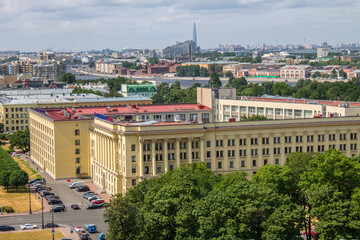 Fototapeta na wymiar SAINT PETERSBURG, RUSSIA-JULY, 20, 2021: panoramic top view of the city with the roofs of houses, the road and trees against the background of green foliage of trees from the bell tower of the Smolny 