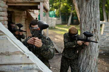 Paintball players in uniform shoots with guns