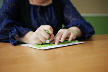 Close-up of disability blind person woman hands writing braille text on paper by using slate and stylus tools making embossed printing for Braille character encoding.