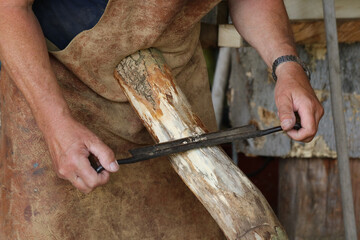 Mann beim Entrinden eines Baumstamms mit dem Zugmesser