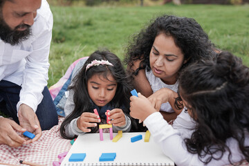 Happy indian family having playful time at city park with colorful wood toys