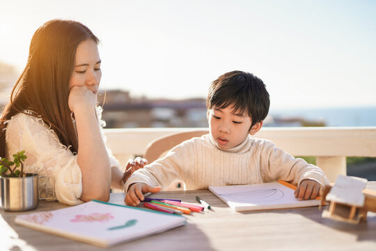 Asian mother doing drawing activities outdoor on patio with little son - Mother and child love