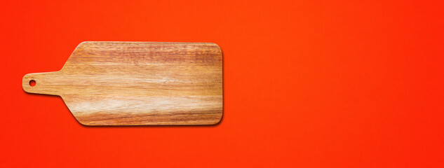 Wooden cutting board isolated on red. Horizontal banner
