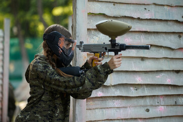 Paintball warrior shoots with gun from the shelter